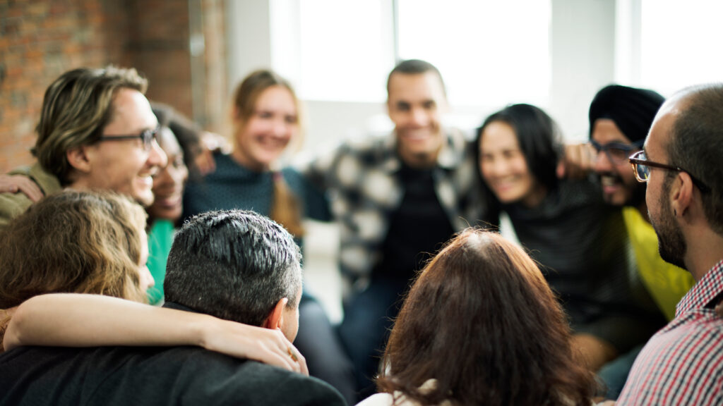 Happy people huddling in a room speaking about business and getting closer.