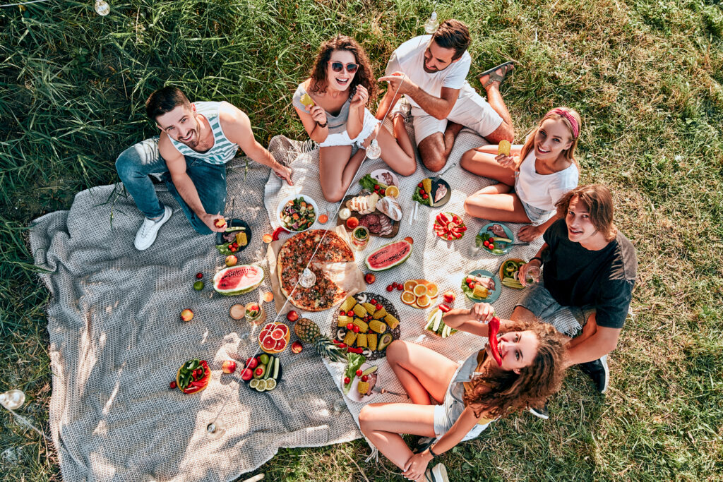 Young people enjoying picnic in park on summer day, top view