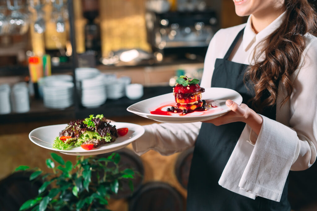  Waiter serving in motion on duty in restaurant. The waiter carries dishes good food 